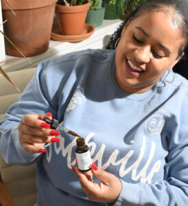 woman in sackville crewneck taking Grounded TONIC CBD tincture