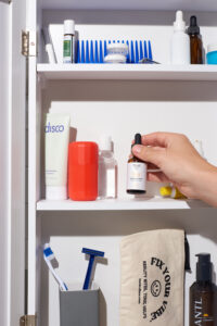 man reaching for Flex TONIC in bathroom vanity medicine cabinet